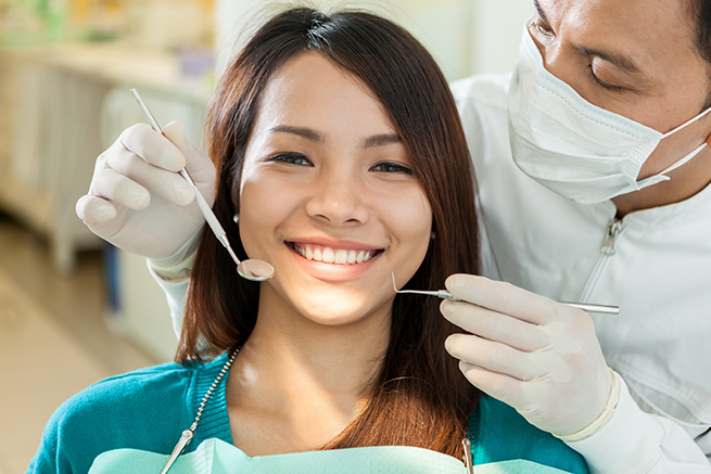 Woman smiling, Dentist holding dental instruments to check his patient