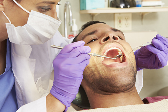 Dentist checking the teeth of the patient using dental instruments