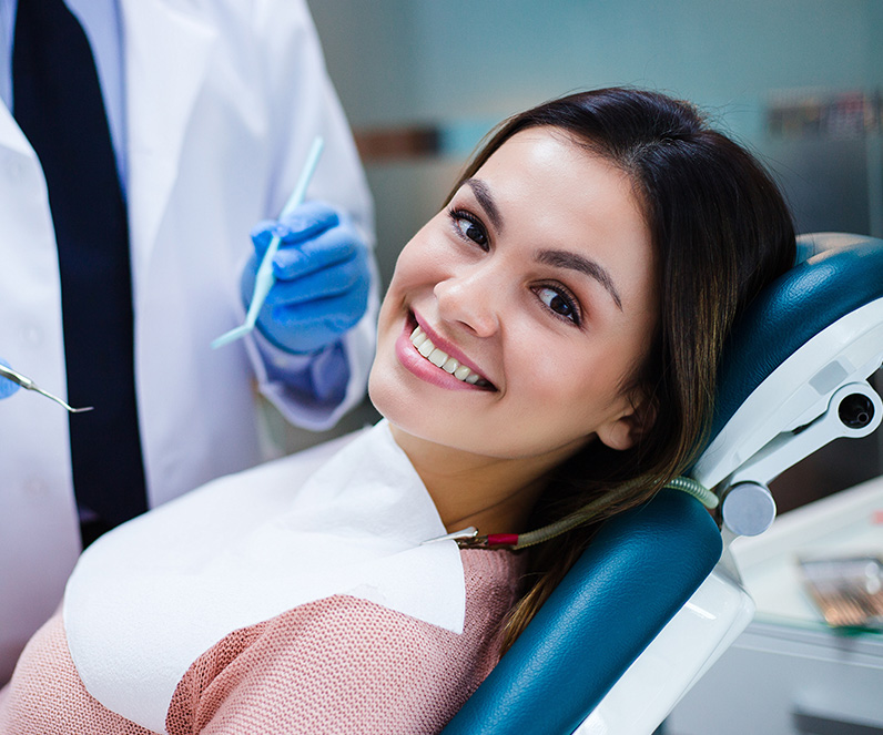 Patient smiling, Dentist holding dental instruments in the background