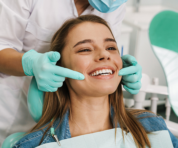 Woman smiling while getting her teeth check up by a dentist